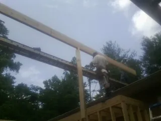 Carpenter setting a ridge beam over a new addition frame — Ice Dam Removal by Roofing Brothers in Grand River