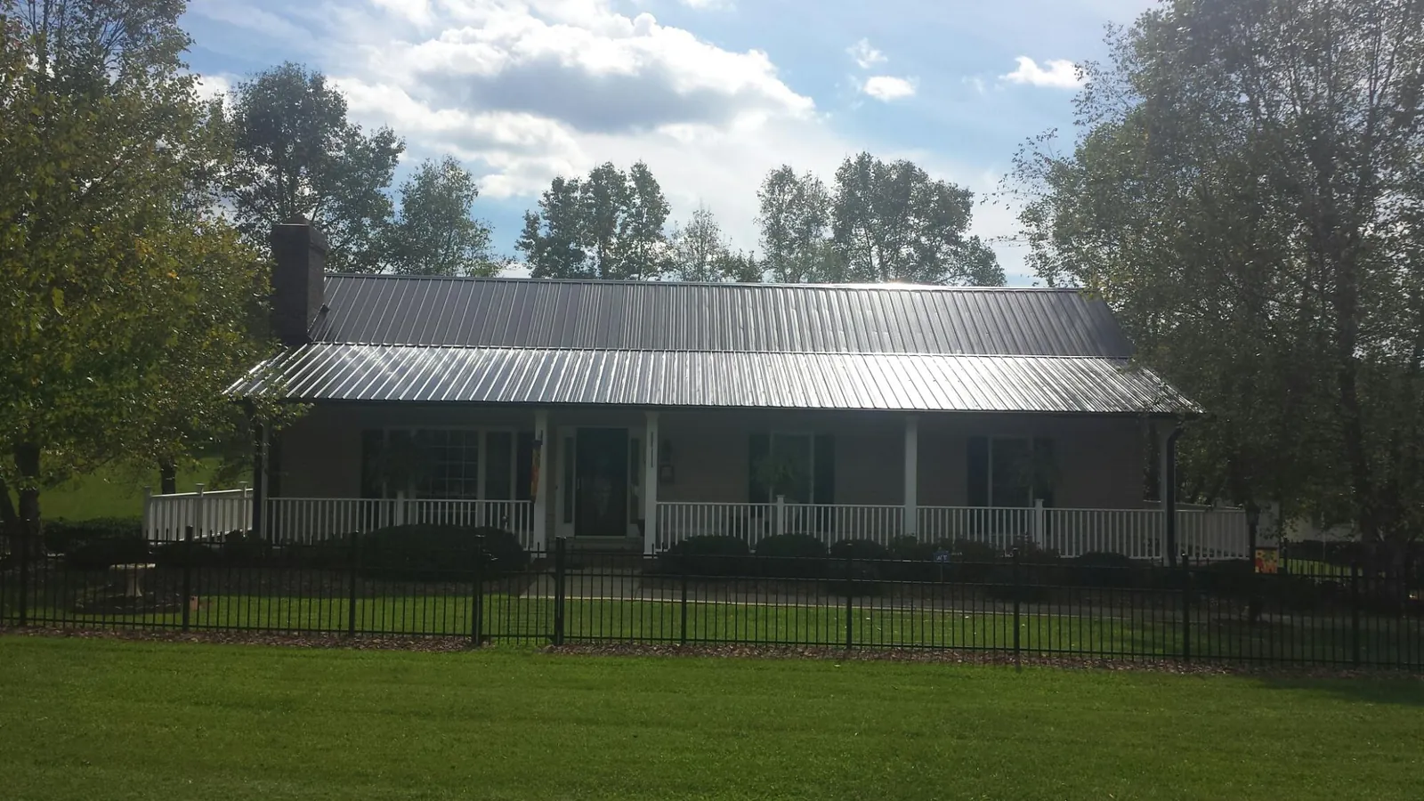 Gray metal roof on a brick ranch with a full width front porch — Gutter Guard Installation work by our crew in Grand River